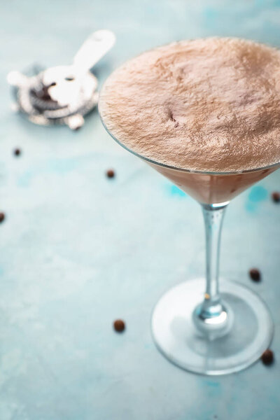 Glass of coffee martini on color background