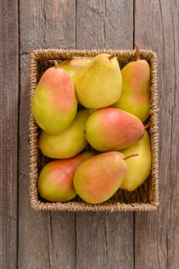 Tahta zemin üzerinde taze armutlar olan sepet.