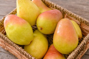 Tahta zemin üzerinde taze armutlar olan sepet.