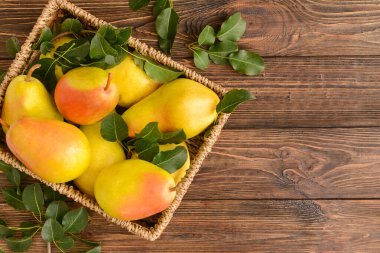 Tahta zemin üzerinde taze armutlar olan sepet.