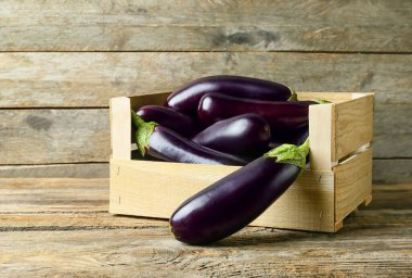 Tahta arka planda taze patlıcanlı kutu.