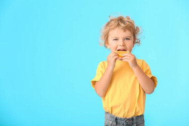 Renkli arka planda turuncu yiyen şirin bir çocuk.