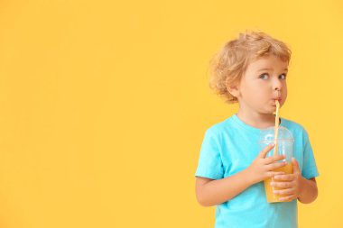 Tatlı küçük çocuk arka planda portakal suyu içiyor.