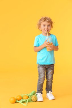 Tatlı küçük çocuk arka planda portakal suyu içiyor.