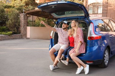 Mutlu aile dışarıda arabanın bagajında oturuyor.