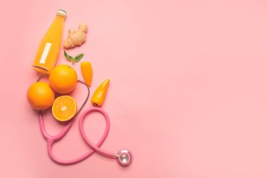 Sağlıklı ürünler, steteskop ve arka planda bir şişe meyve suyu.