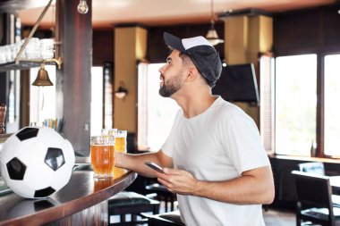 Genç adam barda spor bahisleri oynuyor.
