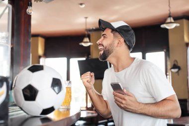 Bardaki spor bahsini kazandıktan sonra mutlu bir genç adam.