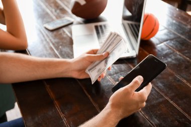 Parası ve cep telefonu olan genç bir adam spor bahisleri oynuyor.