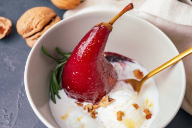 Koyu arka planda kırmızı şarap ve dondurmayla kaplanmış armutlu bir kase, yakın plan.