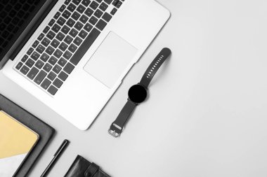 Modern akıllı saat, dizüstü bilgisayar ve hafif arkaplan üzerine not defterleri