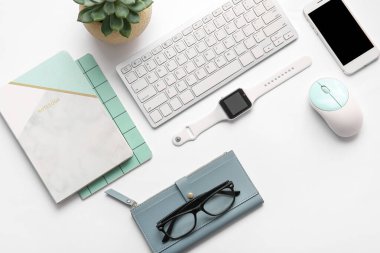 Hafif arkaplanda modern akıllı saat, bilgisayar klavyesi ve cep telefonu bileşimi