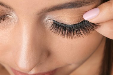 Güzel bir genç kadın takma kirpik takıyor.