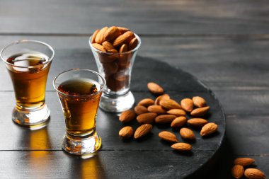 Badem likörlü tepsi ve koyu ahşap arka planda fındıklar.