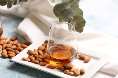 Bir bardak badem likörü ve renkli fındıklı tepsi.