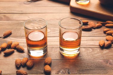 Bir bardak badem likörü ve ahşap arka planda fındık.