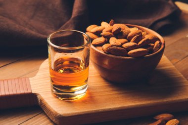 Bir bardak badem likörü ve ahşap arka planda fındık.