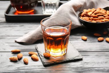 Bir bardak badem likörü ve koyu ahşap arka planda fındık.