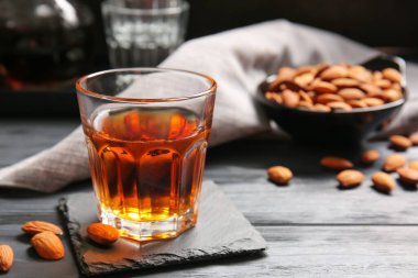 Bir bardak badem likörü ve koyu ahşap arka planda fındık.