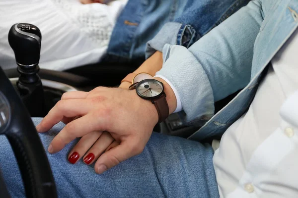 Young couple holding hands in car