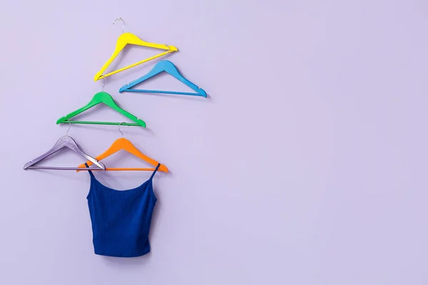 Different hangers with clothes on color background