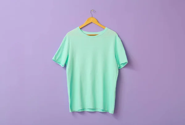 Stylish t-shirt hanging on color background