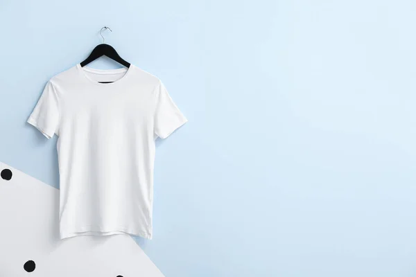 Stylish t-shirt hanging on color background