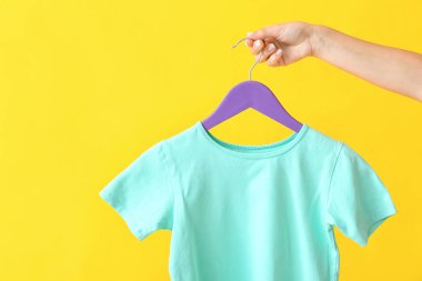 Arka planda tişörtü olan kadın askısı tutuyor