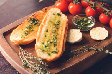 Sarımsaklı kızarmış ekmek ve koyu arkaplanda domates.