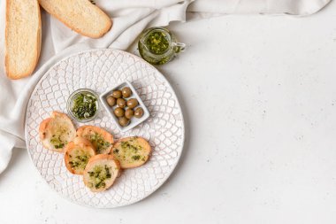 Taze ekmek, sarımsak ve hafif arkaplanda zeytin tabağı.