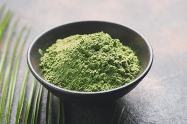 Arka planda pudralanmış kibrit çayı ile kase, yakın plan.