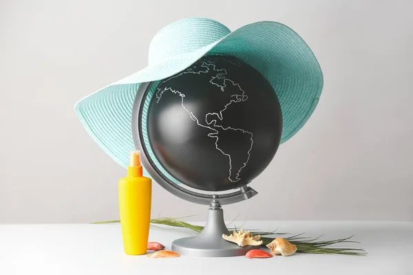 Globe and beach accessories on light background