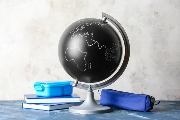Globe with books and pencil bag on light background