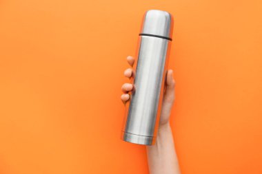 Arka planda termos şişesi olan kadın el.