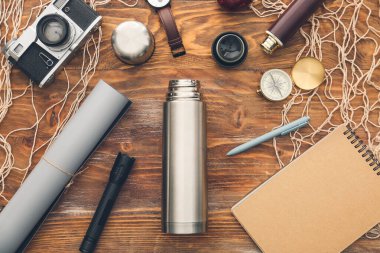 Ahşap arka planda seyahat için modern termos ve ögeler