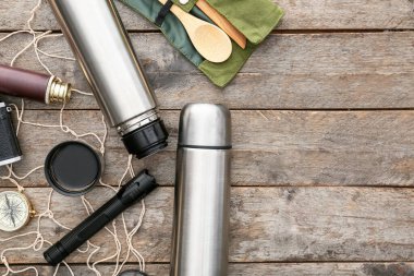 Ahşap arka planda seyahat için modern termos ve ögeler