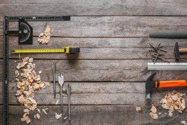 Marangoz aletleri seti ve ahşap arka planda toz gördüm.