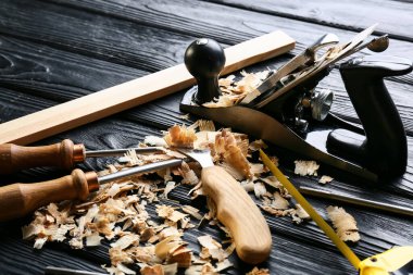 Marangoz aletleri seti ve koyu ahşap arka planda toz gördüm.