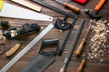 Marangoz aletleri seti ve ahşap arka planda toz gördüm.