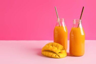 Renkli arkaplanda taze mango suyu şişeleri