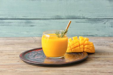 Renkli ahşap arka planda bir bardak lezzetli mango smoothie.