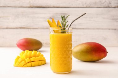 Hafif ahşap arka planda bir bardak lezzetli mango smoothie.