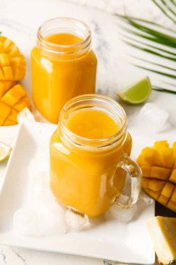 Mason kavanozları hafif arka planda lezzetli mango smoothie