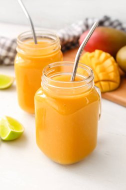 Mason kavanozları hafif arka planda lezzetli mango smoothie