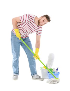 Beyaz arka planda temizlik malzemeleri ve paspası olan genç bir adam.