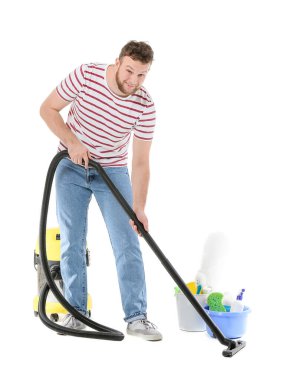 Beyaz arka planda elektrik süpürgesi olan genç bir adam.