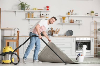 Genç adam mutfakta yerleri süpürüyor.