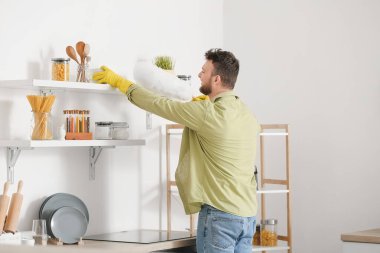 Genç adam mutfağını temizliyor.