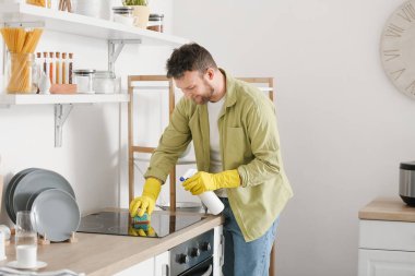 Genç adam mutfağını temizliyor.