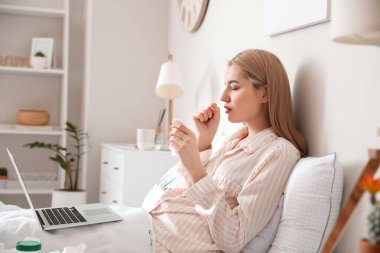 Evde dizüstü bilgisayarı olan hasta genç bir kadın.